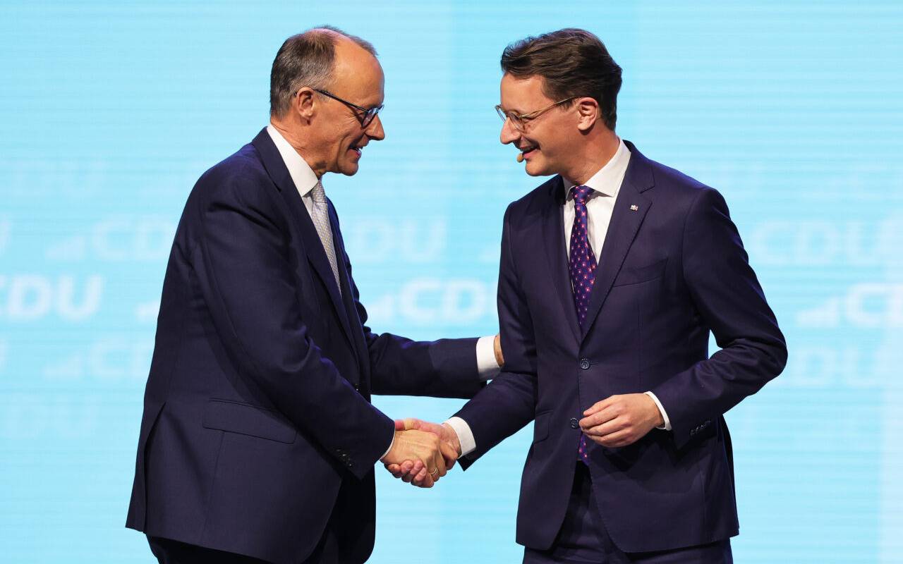 Friedrich Merz (l), CDU-Bundesvorsitzender und Unions-Kanzlerkandidat, und Hendrik Wüst (CDU), Ministerpräsident von Nordrhein-Westfalen, geben sich bei einer Wahlkampfveranstaltung der CDU in der Rudolf Weber-Arena auf der Bühne die Hand.