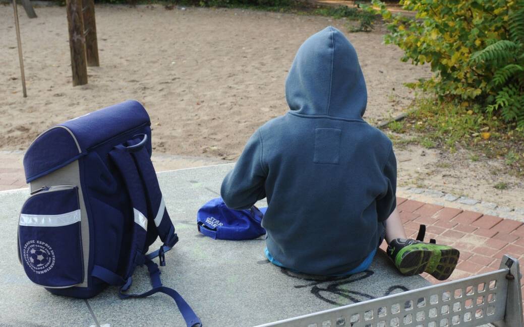 Ein Junge sitzt mit seinem Schulranzen auf einer Tischtennisplatte auf einem Spielplatz. Notorische Schwänzer oder Eltern, die ihre Kinder für einen frühzeitigen Urlaubsbeginn krank schreiben: Eine Verletzung der Schulpflicht kann unangenehme Folgen haben.