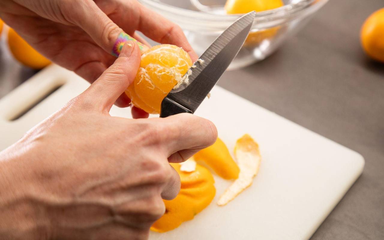 Clementinen werden mit einem Messer von den weißen Fäden befreit