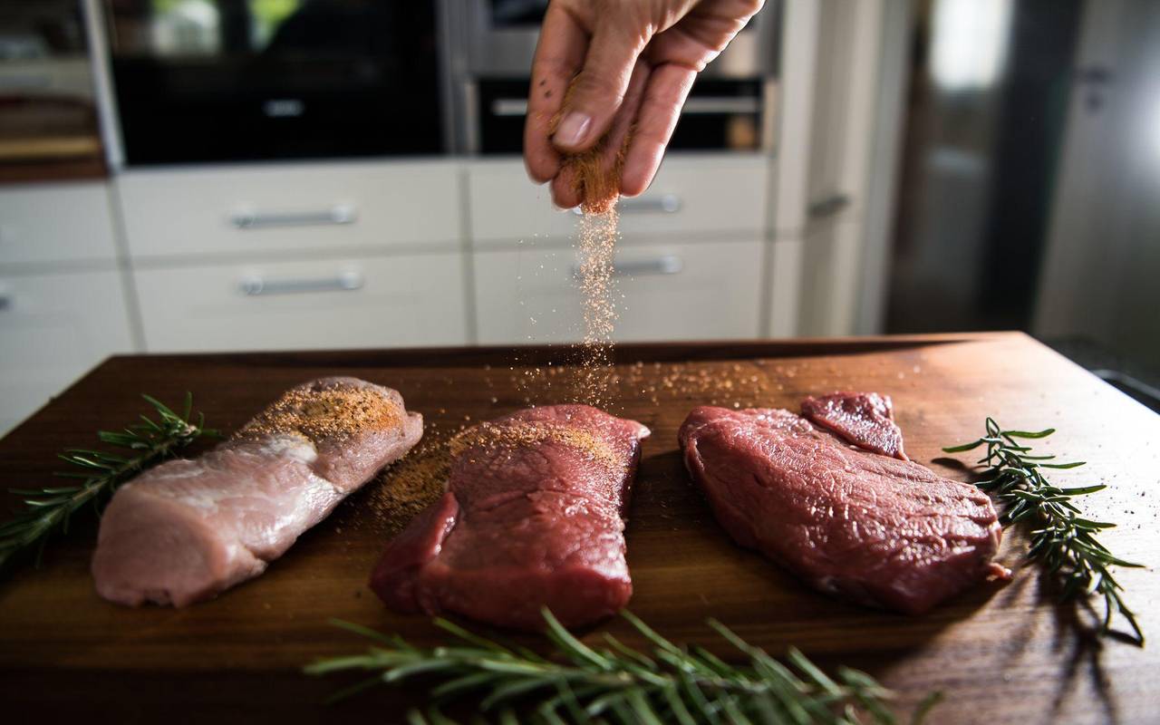 Eine Perosn würzt Fleisch