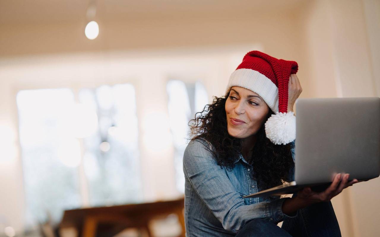 Eine Frau mit Weihnachtsmütze am Laptop