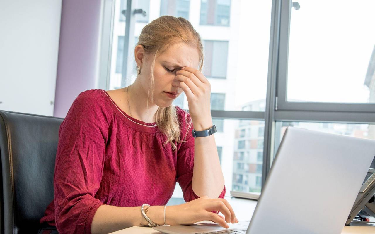 Eine Frau reibt sich die Augen am Arbeitsplatz