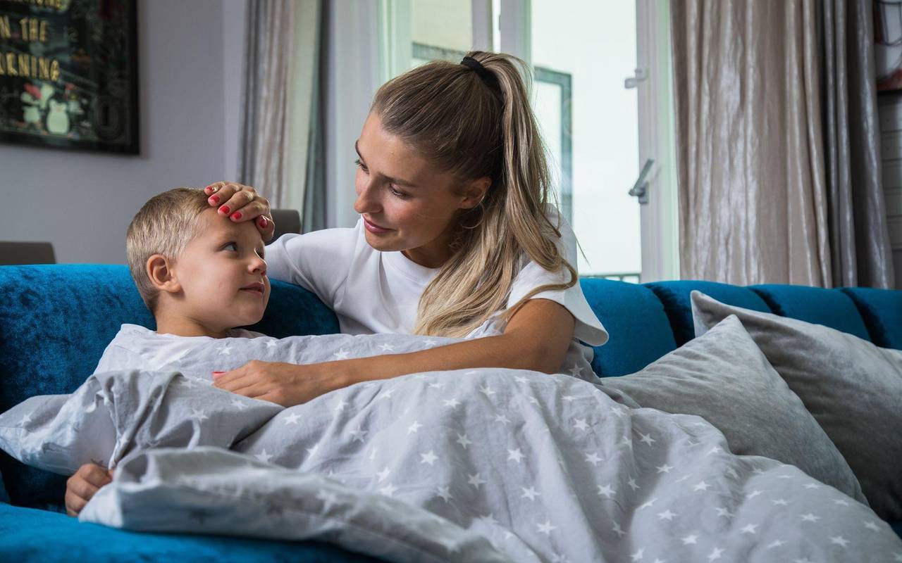Eine Mutter legt ihre Hand auf die Stirn ihres Sohnes