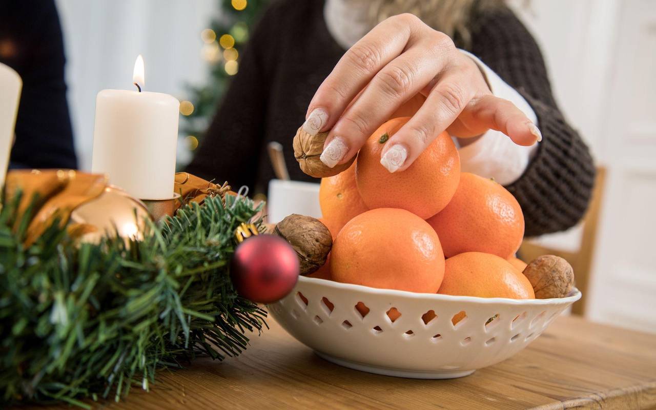 Frau greift nach einer Walnuss in einer Obstschale