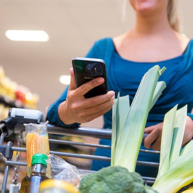 Eine Frau mit Smartphone im Supermarkt