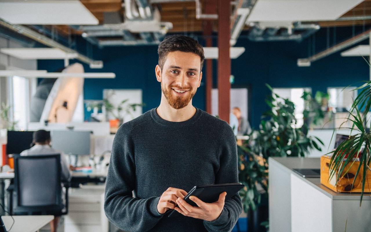 Ein Mann mit Tablet in einem Großraumbüro