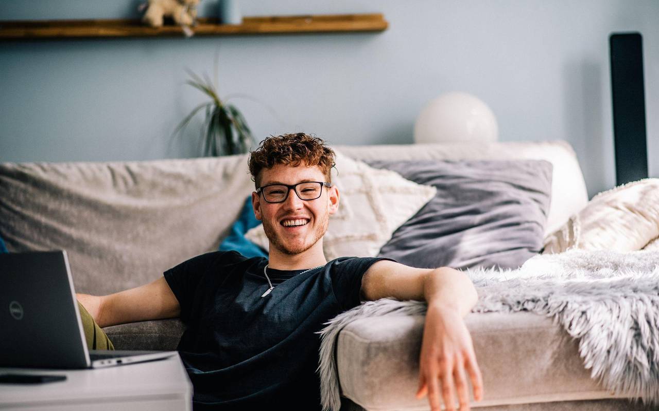 Ein Jugendlicher sitzt im Wohnzimmer vor einem Laptop