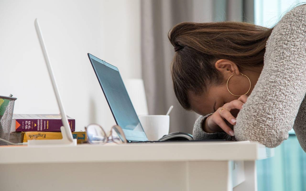 Eine junge Frau legt den Kopf auf den Tisch