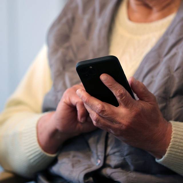Eine Seniorin schreibt eine Nachricht in ihr Handy
