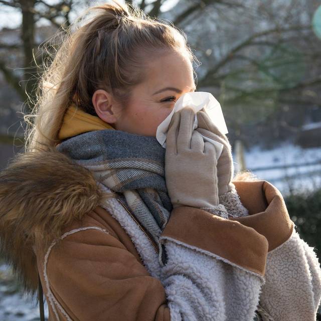 Frau putzt sich im Park die Nase
