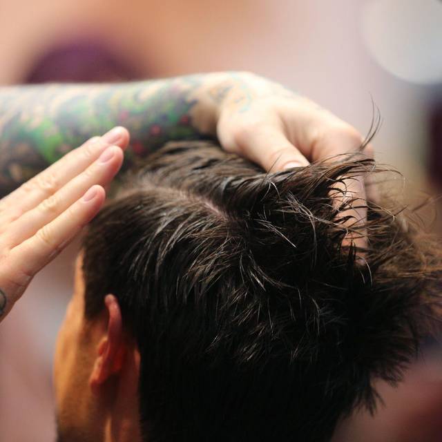 Friseur stylt die Haare eines Mannes mit Haargel