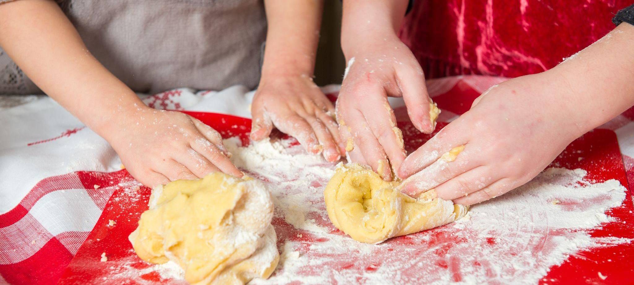 Zwei Mädchen kneten rohen Teig
