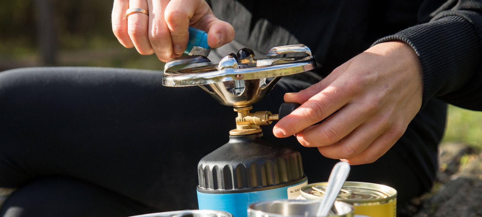 Frau bereitet Essen auf einem Campingkocher zu