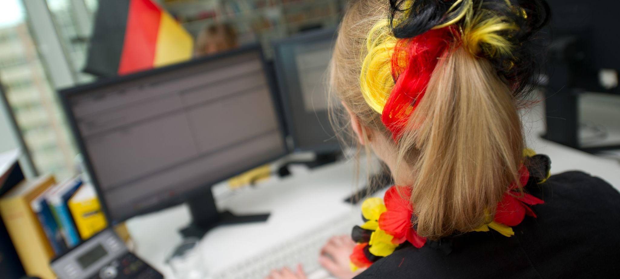 Eine Frau sitzt mit WM-Deko vor einem Computer