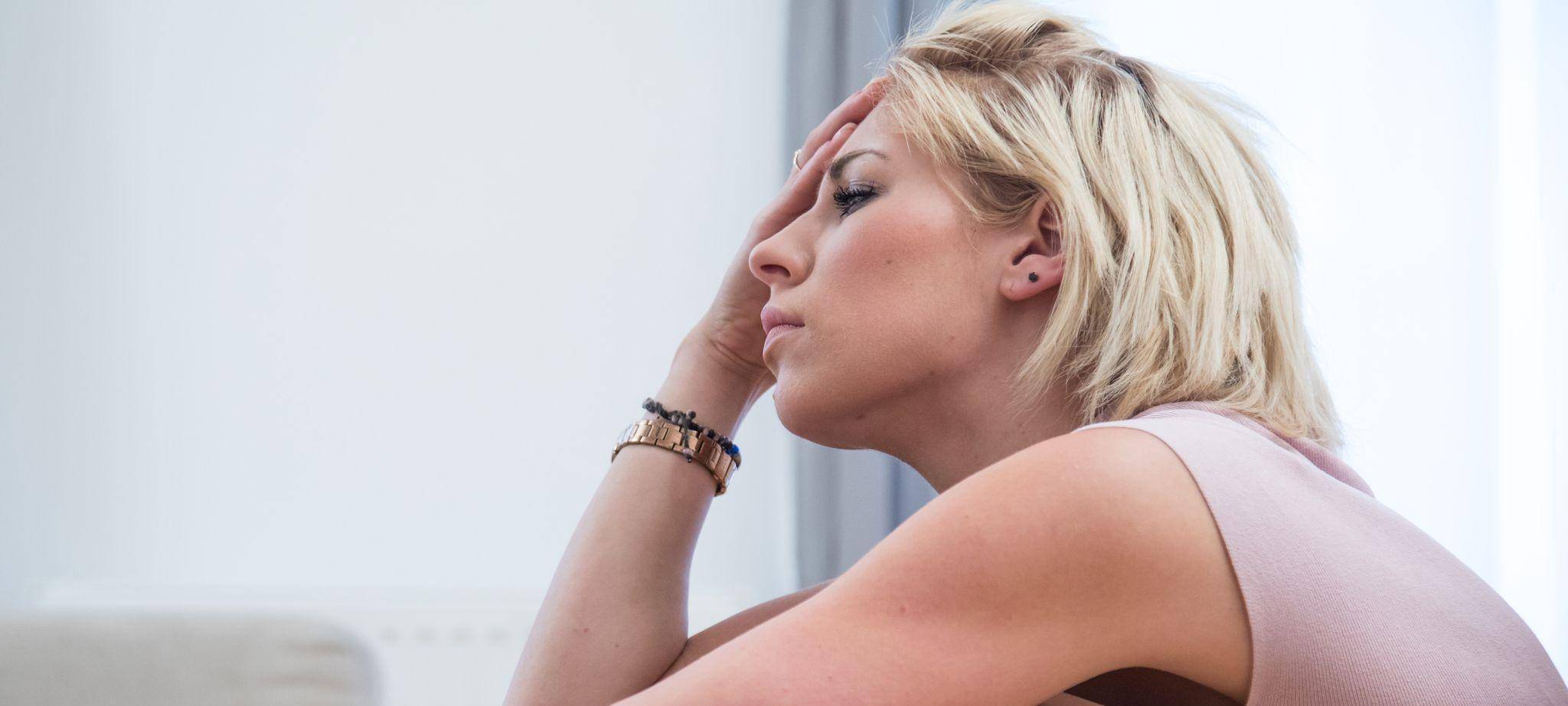 Frau sitzt traurig auf dem Boden ihrer Wohnung