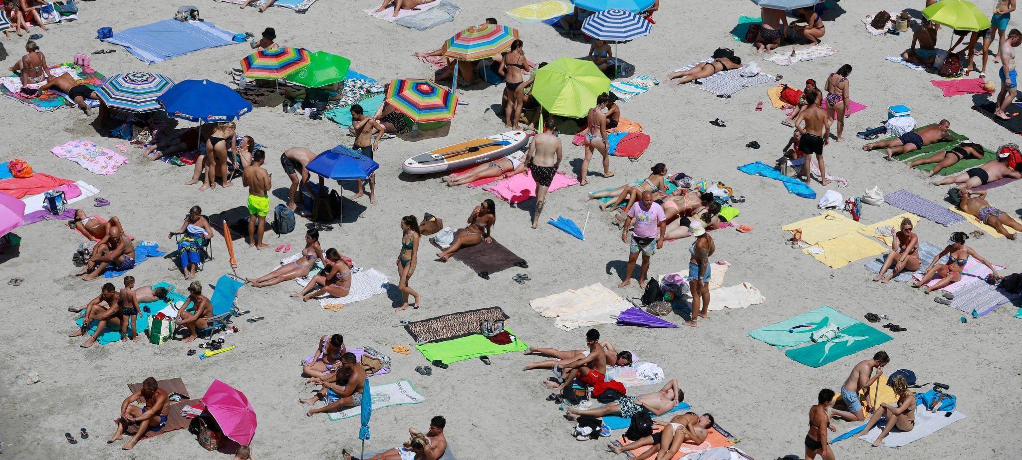 Menschen nehmen einen Sonnenbad am Strand Cala Pi